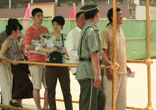 A security man talks with residents at the venue for a vote on demolishment and reconstruction of old buildings in Juixiaqiao Sub-district in Beijing, June 9, 2007. Local government and the real estate developer jointly organize the vote on Saturday to see if majority residents of over 5000 families accept the new compensation policy after failed attempts to reach an agreement through other ways. Both notary officials and supervisors are invited to monitor the vote that runs from 9 a.m. to 9 p.m. at six ballot booths. [Sun Yuqing/www.ttav89.com]
