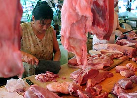 A vendor prepares pork at a market in Shanghai yesterday. ChinaKs far south is on high alert since one person was killed and three infected by a pig-borne disease that had left nearly 40 dead in the southwest. The latest person killed by the disease, caused by the Streptococcus suis bacterium, had handled infected pork, Xinhua news agency said on Tuesday. The three other victims, all butchers, also likely had contact with infected meat. 