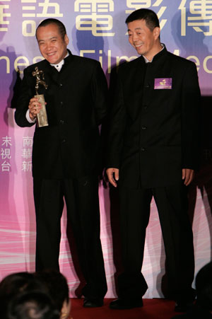 Chinese director Ning Hao (L) holds a trophy for Best Director for his movie