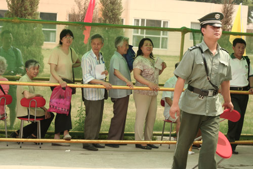 A security man carries a charir at the venue for a vote on demolishment and reconstruction of old buildings in Juixiaqiao Sub-district in Beijing, June 9, 2007. Local government and the real estate developer jointly organize the vote on Saturday to see if majority residents of over 5000 families accept the new compensation policy after failed attempts to reach an agreement through other ways. Both notary officials and supervisors are invited to monitor the vote that runs from 9 a.m. to 9 p.m. at six ballot booths. [Sun Yuqing/www.ttav89.com]